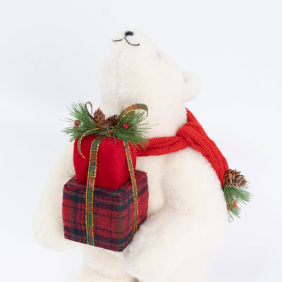 White plush polar bear with Christmas gifts and red scarf under holiday decor