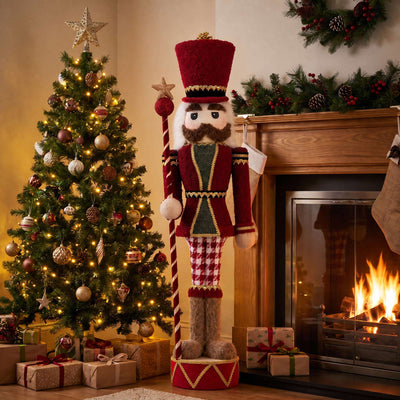 Christmas living room with decorated tree, nutcracker, fireplace, and gifts