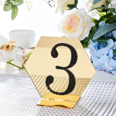 Gold hexagonal table number 3 with black embellishments on a table setting.