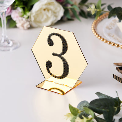 Gold mirrored table number 3 stand on a white table setting.