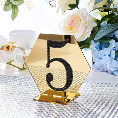 Gold hexagon table number 5 with decorative black accents on a table setting.