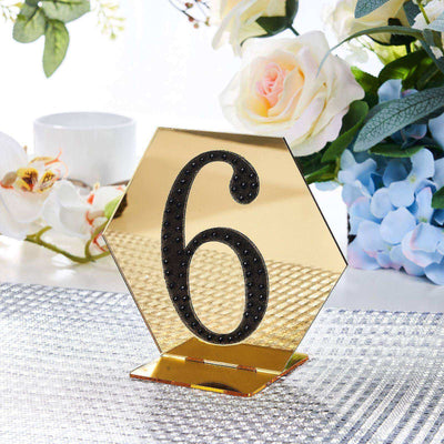 Gold hexagon table number 6 with rhinestone accents on a decorative table setting.