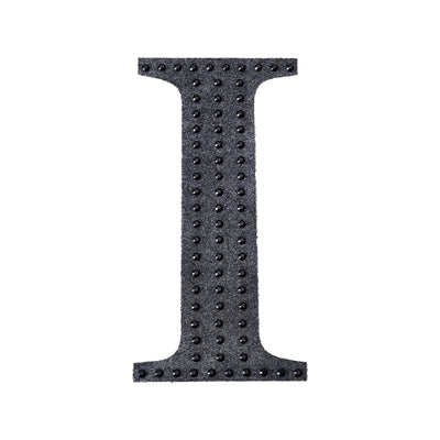 Black textured letter "I" with raised dots on a plain background