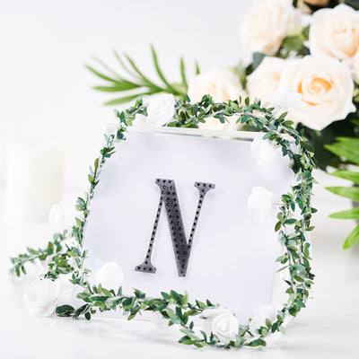 Decorative letter "N" with floral wreath and background flowers