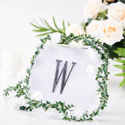 Decorative letter "W" with floral accents on a clear background.