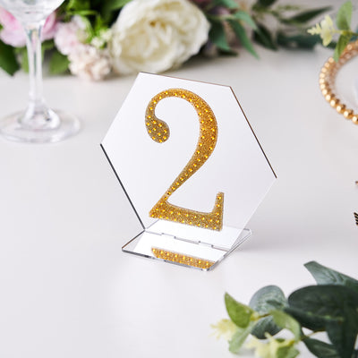 Gold glitter table number 2 in a hexagon shape on a white background