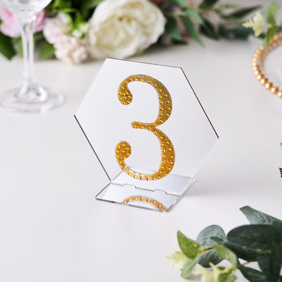 Gold glitter number 3 table centerpiece on a mirrored hexagon base.