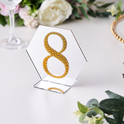 Gold glitter number 8 table centerpiece on a clear stand.