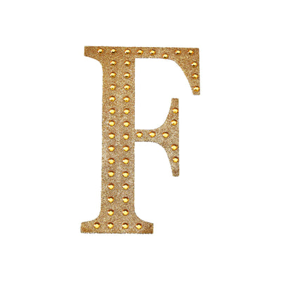 Gold decorative letter "F" with studded embellishments on a white background.