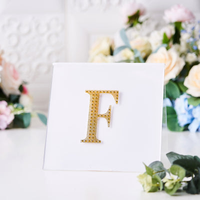 Gold letter "F" embellishment on a white card with floral background.