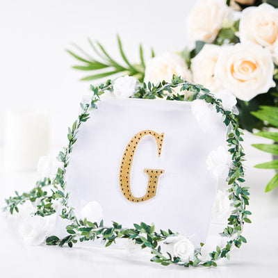 Gold letter G decoration with floral embellishments on a clear background.