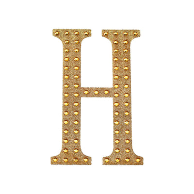 Gold studded letter "H" on a plain white background.