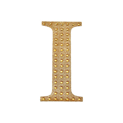Gold studded letter "I" decorative piece on a white background