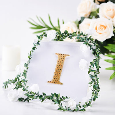 Gold letter "I" decor with floral accents on a clear backdrop.