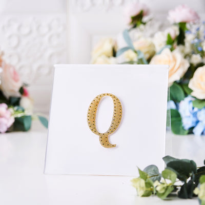 Gold rhinestone letter Q on a white card with floral background.