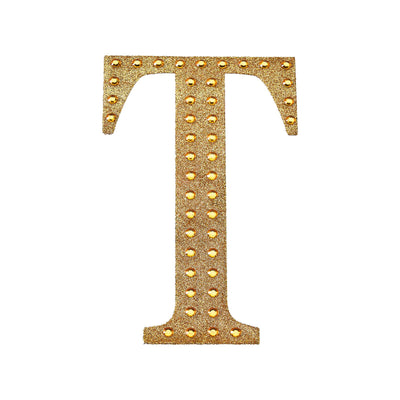 Gold studded letter "T" on a white background.