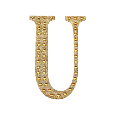 Gold glitter letter "U" with rhinestones on a white background.