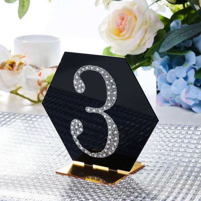 Black table number stand with rhinestone embellishments, shaped like a hexagon.