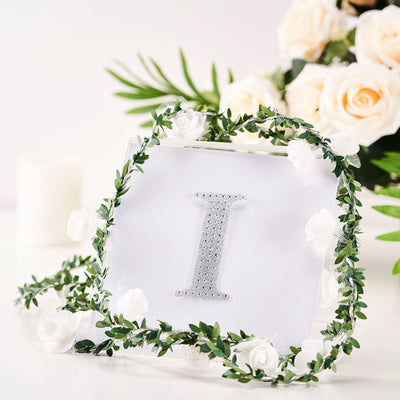 Decorative letter "I" with floral accents and greenery in a studio setting.