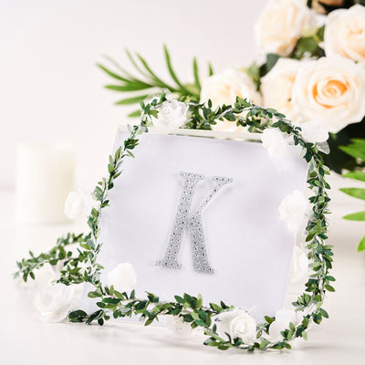Decorative letter "K" with floral accents on a clear background.