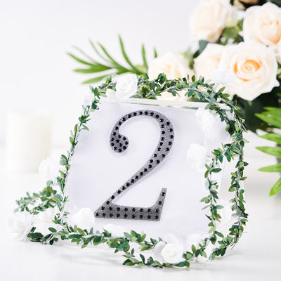 Decorative table number 2 with greenery and flowers on a white background.