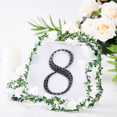Decorative table number 8 with floral accents and greenery.