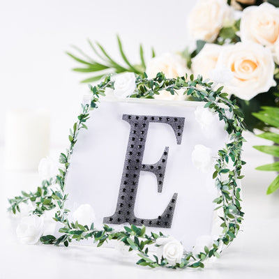Decorative letter "E" surrounded by floral accents and greenery.