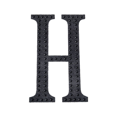 Black felt letter "H" with studded detail on a white background.
