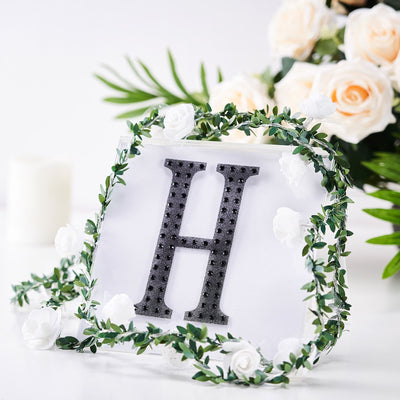 Decorative letter "H" surrounded by floral accents on a white background.