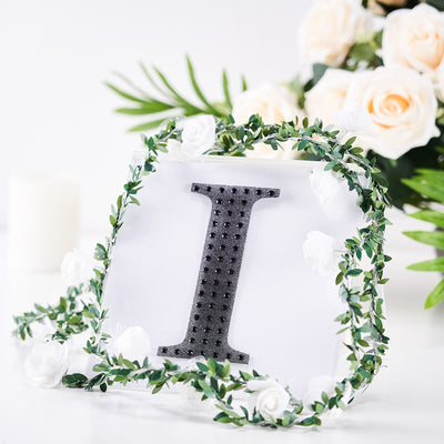 Decorative letter "I" with floral wreath on a white background