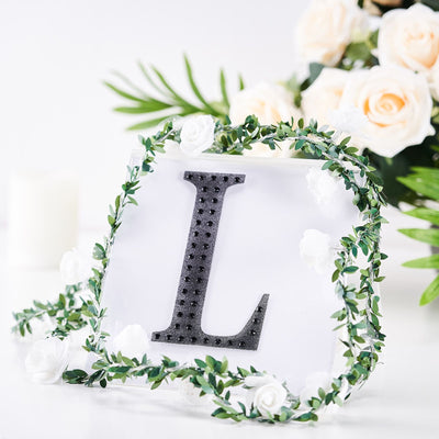 Decorative letter "L" with floral accents on a white background.