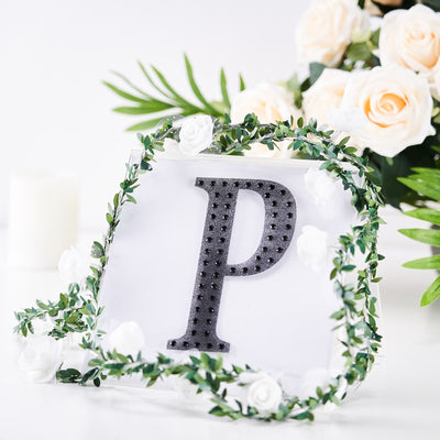 Black letter "P" decorative item with floral accents on a white background.