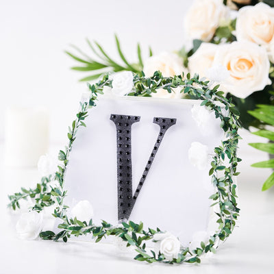 Decorative letter "V" with floral accents on a clear backdrop.
