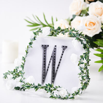 Decorative letter "W" with floral garland and roses, studio shot.