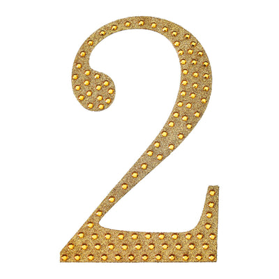 Gold glitter number two with rhinestones on a plain background.
