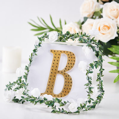 Gold letter "B" decor with floral accents on a white background.