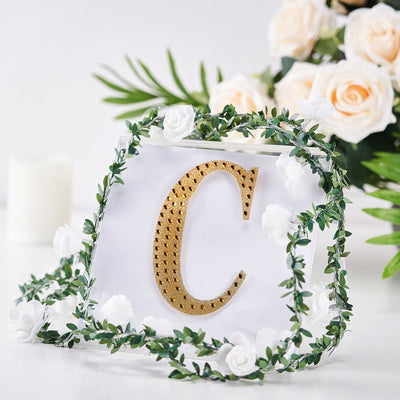 Decorative acrylic letter "C" with gold accents and floral arrangement.