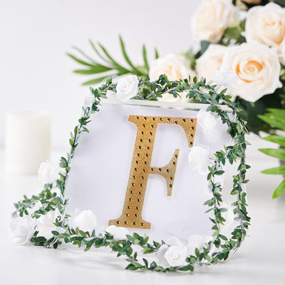 Gold letter "F" with floral wreath on a white background.