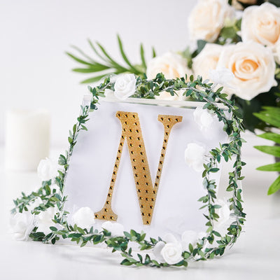 Gold letter "N" decor surrounded by floral accents and greenery.