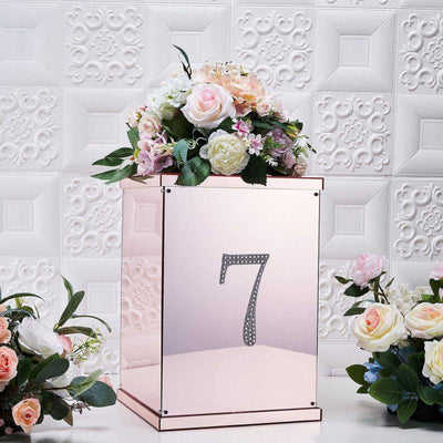 Rose gold number 7 gift box with floral arrangement on a textured white background.
