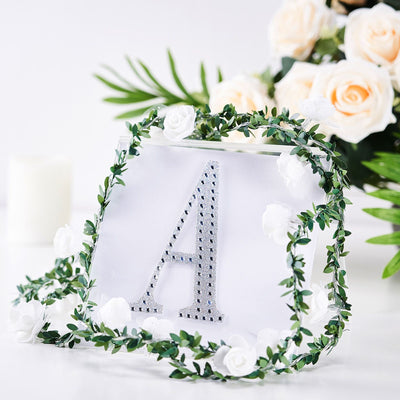 Silver rhinestone letter "A" surrounded by floral greenery and roses.