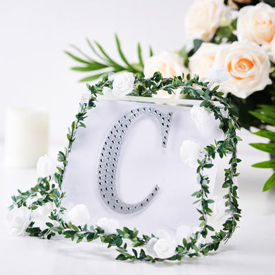 Decorative letter "C" adorned with flowers and greenery on a white background.