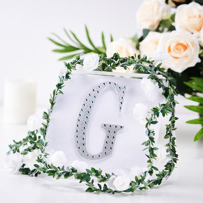 Clear acrylic letter "G" adorned with rhinestones and floral accents.