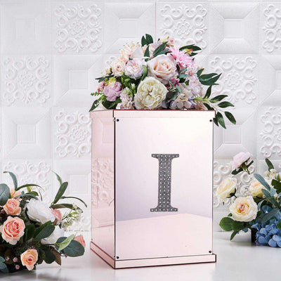 Mirrored floral arrangement box with decorative letter "I" and flowers.
