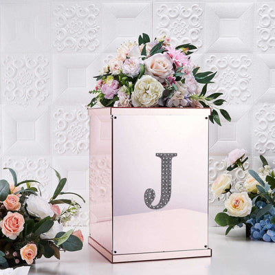 Rose gold floral display box with letter "J" and flowers on a textured background.