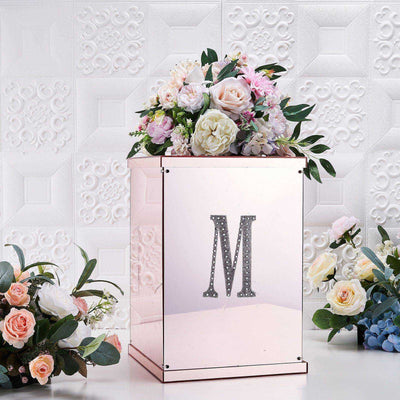 Decorative floral arrangement in a mirrored box with letter 'M' accent.