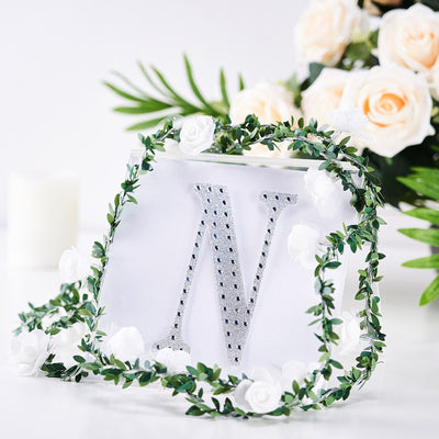 Decorative letter "N" with rhinestones surrounded by floral accents.