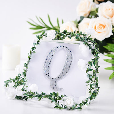 Decorative acrylic letter Q adorned with flowers and greenery.