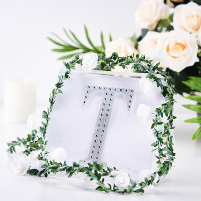 Decorative letter "T" with floral garland and roses in soft styling.