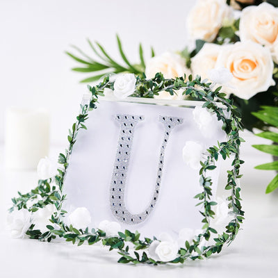 Decorative letter "U" in a clear display with floral accents.